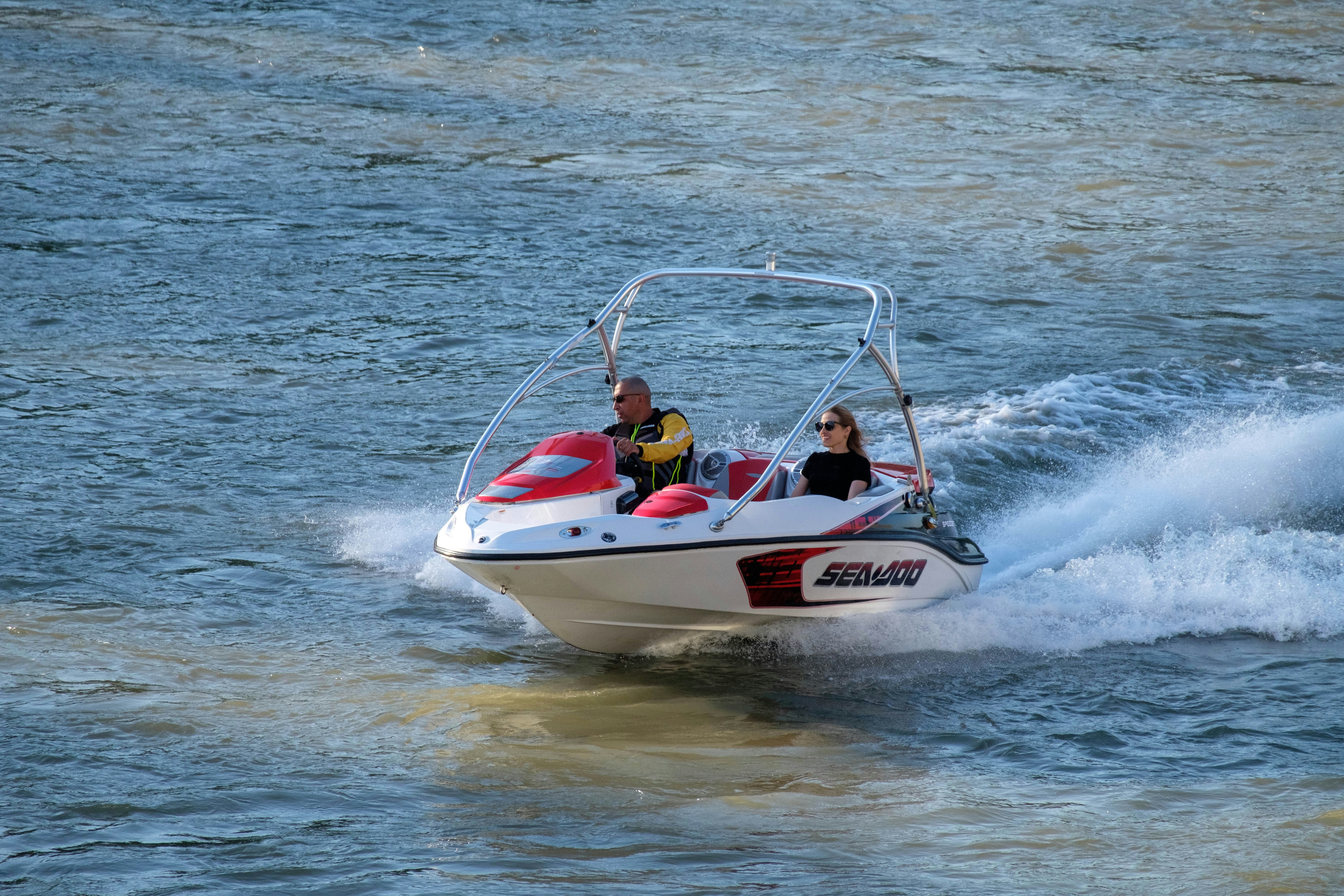 2 men riding on white and red speedboat during daytime